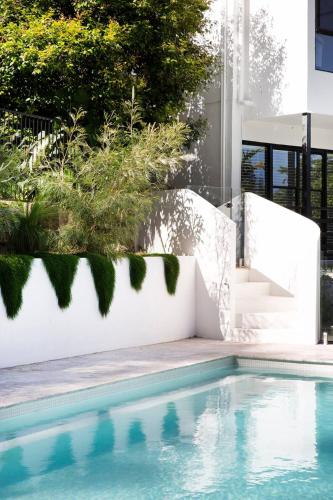 a swimming pool in a yard with a white wall and stairs at Coral villa in Byron Bay