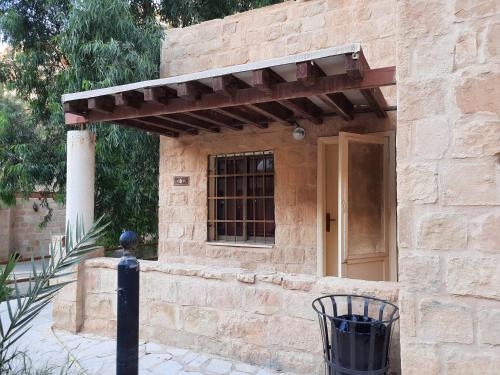 a brick building with a wooden awning on it at Afra Hot Springs Chalets in Tufailah