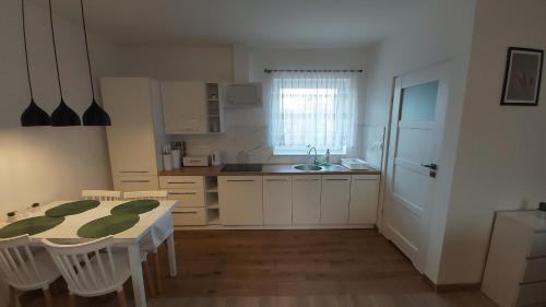 a kitchen with a table and chairs and a sink at Apartament Szmaragdowy in Dąbki