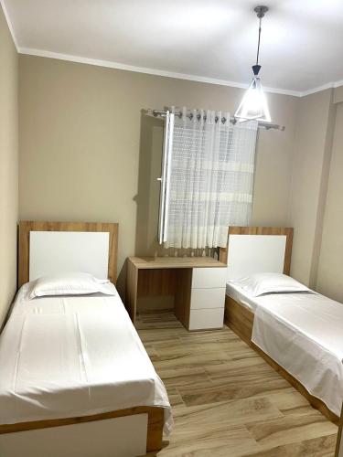 two beds in a room with a window at Twentysix Apartment in Shkodër
