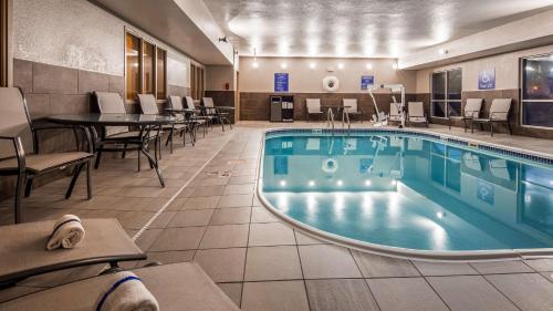 una piscina en una habitación de hotel con mesas y sillas en Best Western Greeley, en Greeley