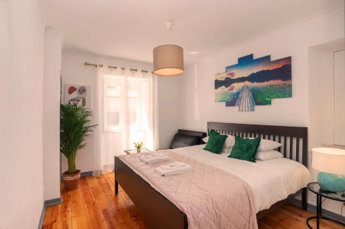 a bedroom with a large bed with green pillows at Happy Holiday Cascais - Garden in Cascais