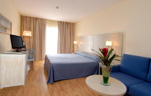 um quarto de hotel com uma cama e um sofá azul em AGH Canet em Canet de Berenguer