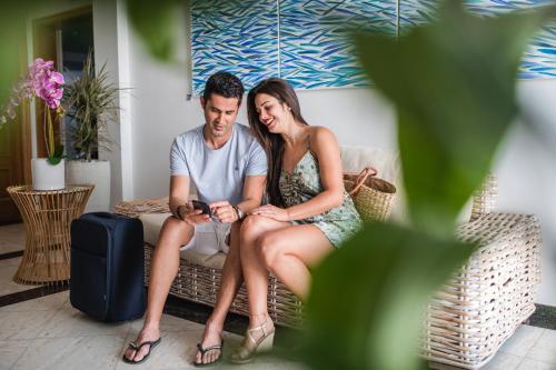 a man and woman sitting on a couch looking at a cell phone at ALTAVISTA APARTAHOTEL-Adults Only over 14 in Morro del Jable