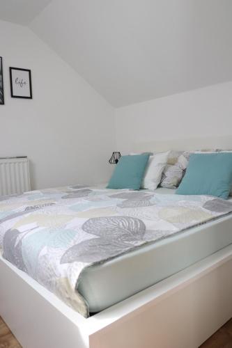 a white bed with blue pillows on it at Lusht'n apartma in Žirovnica