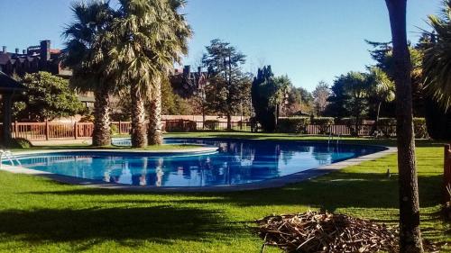 a swimming pool with palm trees in a park at Casa en Condominio Foresta central y a 200 mt playa in Pucón