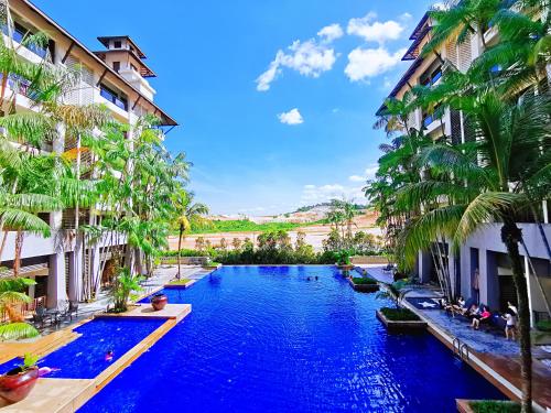 a swimming pool between two buildings with palm trees at Amazing Resort Suite at Pulai Springs Resort in Johor Bahru