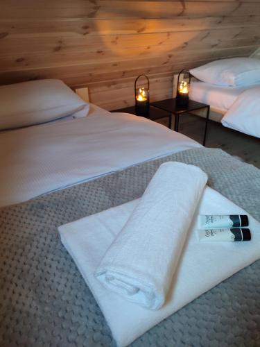 a bedroom with two beds with white towels and two lamps at Domki przy plaży in Ryn