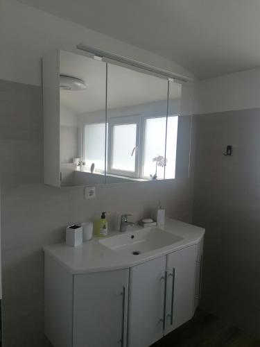ein weißes Bad mit einem Waschbecken und einem Fenster in der Unterkunft Ferienwohnung Andreea in Saarlouis