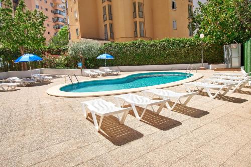 a swimming pool with white chairs and umbrellas at Don Gregorio-Fincas Benidorm in Benidorm