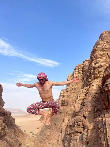 a man jumping off a cliff on the beach at Wadi Rum Magic Camp in Wadi Rum