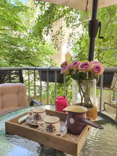 una mesa con tazas y un jarrón con flores. en Apartments Aida, en Sarajevo