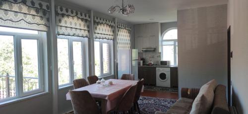 a dining room with a table and some windows at Brick House in Lahıc