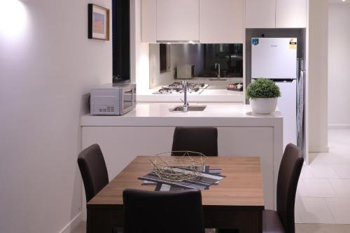 a kitchen with a table with chairs and a refrigerator at Flinders Street Apartments in Melbourne