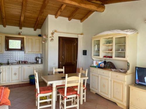 uma cozinha com armários brancos e uma mesa e cadeiras em PUNTA MOLARA em Monte Petrosu