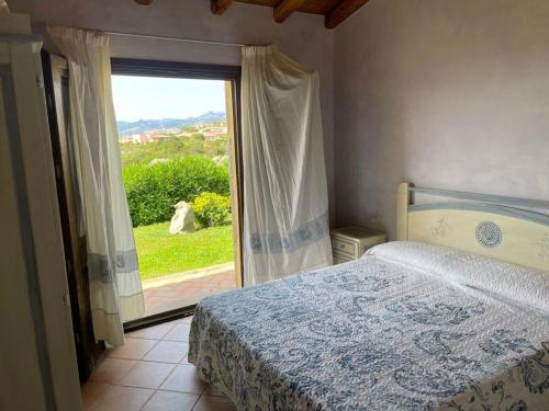 um quarto com uma cama e uma grande janela em PUNTA MOLARA em Monte Petrosu