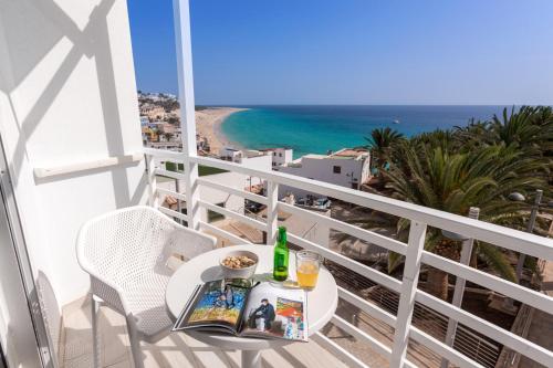 a table on a balcony with a view of the ocean at ALTAVISTA APARTAHOTEL - Adults only in Morro del Jable
