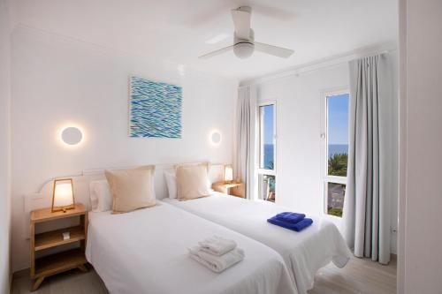 een witte slaapkamer met een bed met handdoeken erop bij ALTAVISTA APARTAHOTEL - Adults only in Morro del Jable