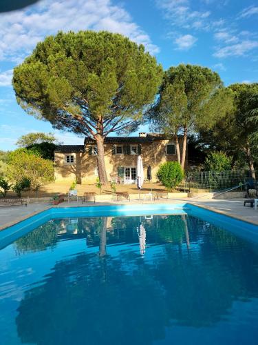 une piscine en face d'une maison avec un arbre dans l'établissement Chambre Malon Mas Bel Esperance, à Saint-André-dʼOlérargues
