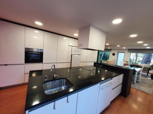 a kitchen with white cabinets and a black counter top at Cabedelo Beach House in Viana do Castelo
