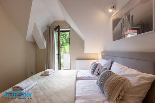 1 dormitorio con 1 cama con sábanas y almohadas blancas en Apartamenty BlueSky - Pusta 8 - blisko szlaków i wyciągów en Karpacz