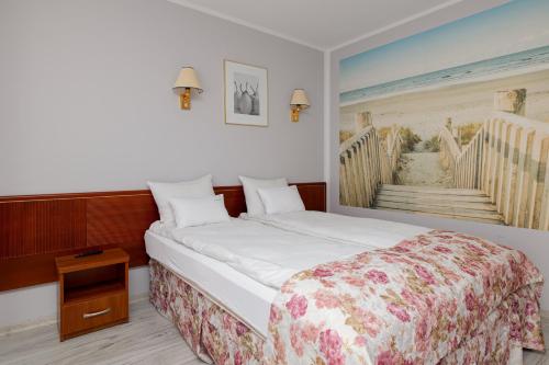 um quarto com uma cama com uma pintura de uma praia em Willa Rawia em Rewal