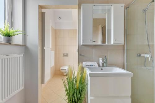 Baño blanco con lavabo y aseo en Apartamenty Piamola Willa Zatoka, en Kąty Rybackie