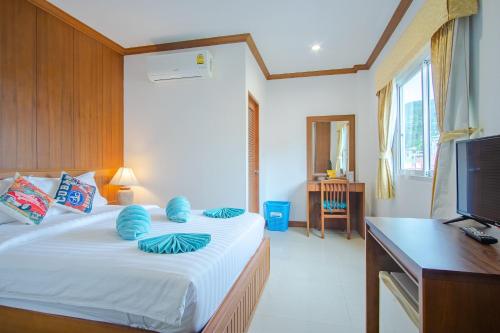 Schlafzimmer mit einem Bett, einem Schreibtisch und einem TV in der Unterkunft Pipikuku Hotel & Restaurant in Patong Beach