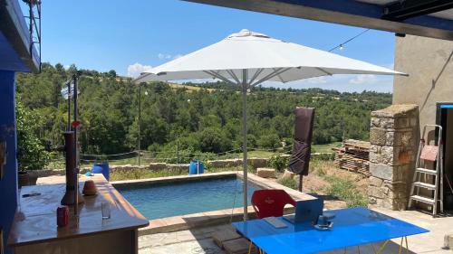 a pool with an umbrella and a table with a computer at Cal Talaia in La Glorieta