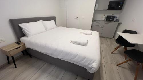 a bedroom with a bed with white sheets and a desk at Morski Val in Piran