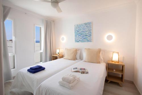 a white bedroom with two beds and two windows at ALTAVISTA APARTAHOTEL-Adults Only over 14 in Morro del Jable
