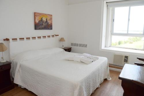 a white bedroom with a bed with two towels on it at Aguas del Monte Hotel SPA in San Miguel del Monte