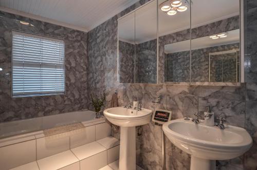 a bathroom with two sinks and a bath tub at Sunset Villa in Yzerfontein