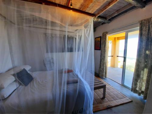 a bedroom with a bed with a canopy at Casa Malcampo in Praia do Tofo