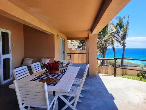 a table and chairs on a porch with the ocean at Casa Malcampo in Praia do Tofo