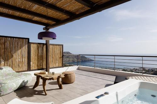 a balcony with a hot tub and a table at Fedra Suites in Plakias