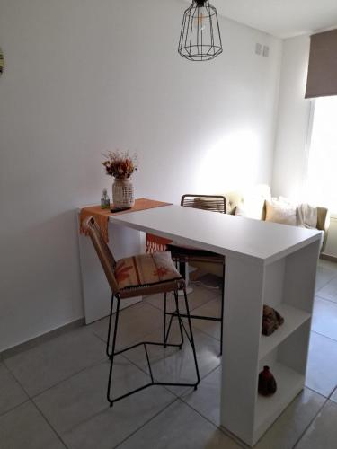 a white table and a chair in a living room at Departamento moderno y luminoso, en planta baja, con patio y excelente ubicación in Rafaela