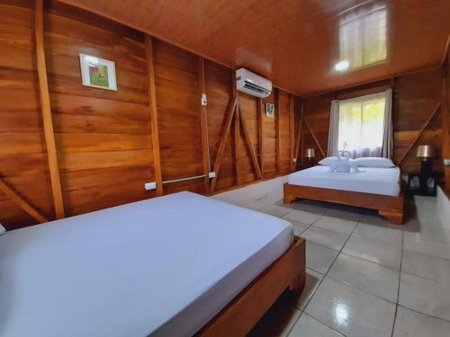 two beds in a room with wooden walls at Cabaña Rural el Mirador in Fortuna