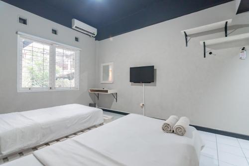 a white room with two beds and a tv at RedDoorz At Home 33 Bandung in Bandung
