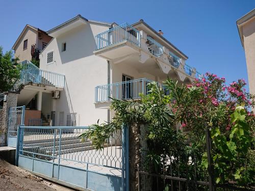 a white house with a blue fence and flowers at Apartments Zolotaya Rybka in Utjeha