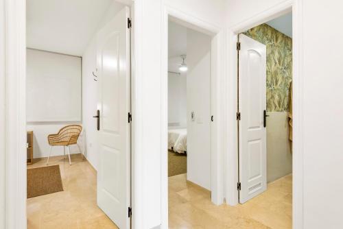 a hallway with white doors and a room with a chair at Beach apartment with terrace and private parking in Radazul