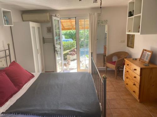 a bedroom with a bed and a dresser and a sliding glass door at retreat studio in Santa Eularia des Riu