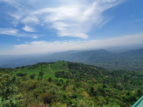 an aerial view of a green hill with trees and mountains at CHILLAX Resorts Palakkayam THATTU in Paithalmala