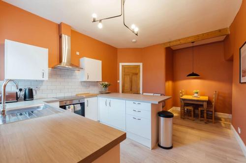 a kitchen with white cabinets and an orange wall at The Riverside Apartment (free parking) in Stirling