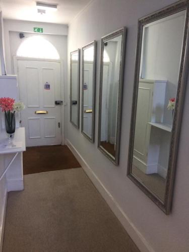 a bathroom with three mirrors and a hallway with a door at Notting Hill Charm -Sleeps 5 - Urban Retreat in London