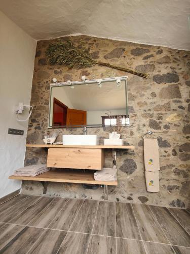 a bathroom with a vanity and a mirror on a stone wall at Casa Rural El Borbullón in Teror