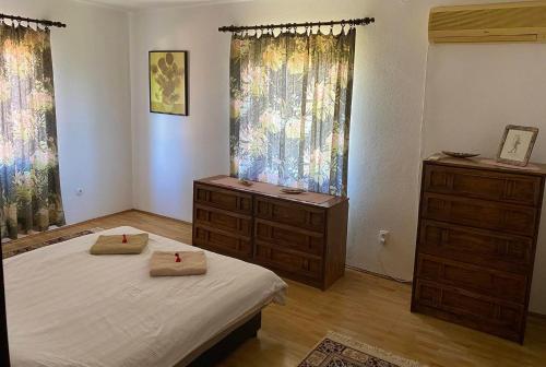 a bedroom with a bed and a dresser and windows at Skupljen Resort: Enjoy the Freedom! in Vladimirci