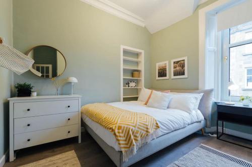 a bedroom with a bed with a dresser and a mirror at Stylish Stirling Apartment - free parking in Stirling