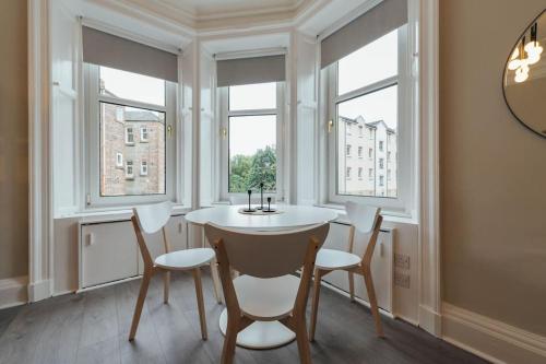a dining room with a table and chairs and windows at Stylish Stirling Apartment - free parking in Stirling