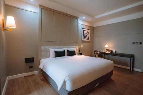 a bedroom with a large white bed and a desk at Hotel Thomas Bangkok in Makkasan